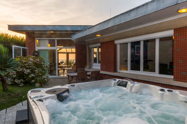 Maison de plage familiale en Normandie. Les baies vitrées du séjour dominent la mer.