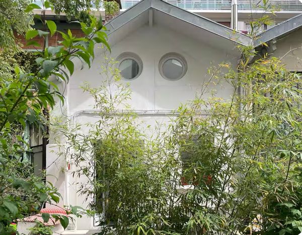 Maison d'artiste avec une terrasse dans un jardin.